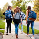 A group of girls walking together on a sidewalk in a residential neighborhood