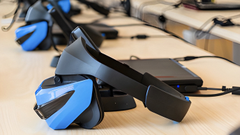 Blue and black virtual reality headsets perched in a line on a countertop 