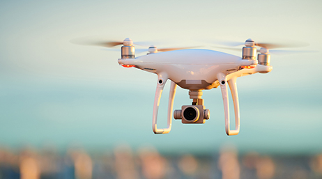 Eine scharf dargestellte in der Luft schwebende weiße, moderne Drohne 
