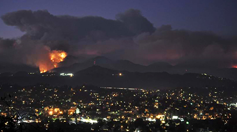 Mountains on fire at night with large smoke clouds billowing above the foothills of Los Angeles, California 