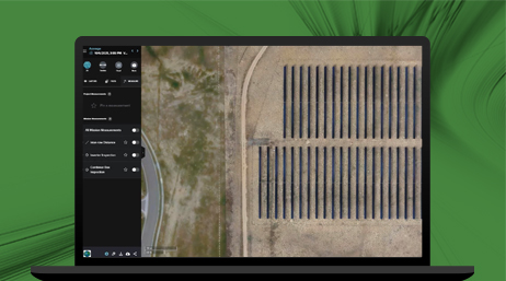 A laptop computer displaying an aerial view a solar farm and a sidebar dashboard