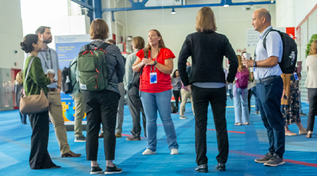 People standing in a circle talking to each other in a large indoor event space