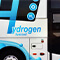 A passenger bus captured in motion with the words “Hydrogen fuel cell” on the side