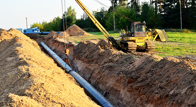 A pipeline being placed in a dug ditch