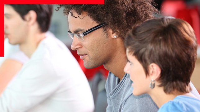 Photo of three casually dressed attendees in a group seminar setting gazing to the left at an unseen speaker or screen