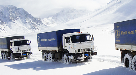 World Food Programme (WFP) snow trucks drive through a snow covered mountain range