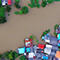 An aerial view of homes and trees flooded with muddy water