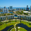 Aerial image of a modern seaside city full of skyscrapers and palm trees with the ocean horizon in the background