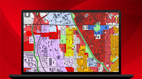 A laptop displaying a map with red, orange, green, purple, and white sections in ArcGIS Pro