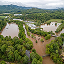 Aerial image of an agricultural residential area filled with dense green trees and heavily flooded with brown floodwater