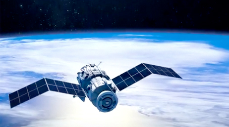 A photo of a blue and white satellite in orbit above a hazy cloud-covered Earth with a strip of black outer space sky across the top