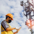 Person looking at a smart device near a telecommunications tower