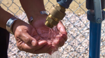 Hands under a water faucet outside