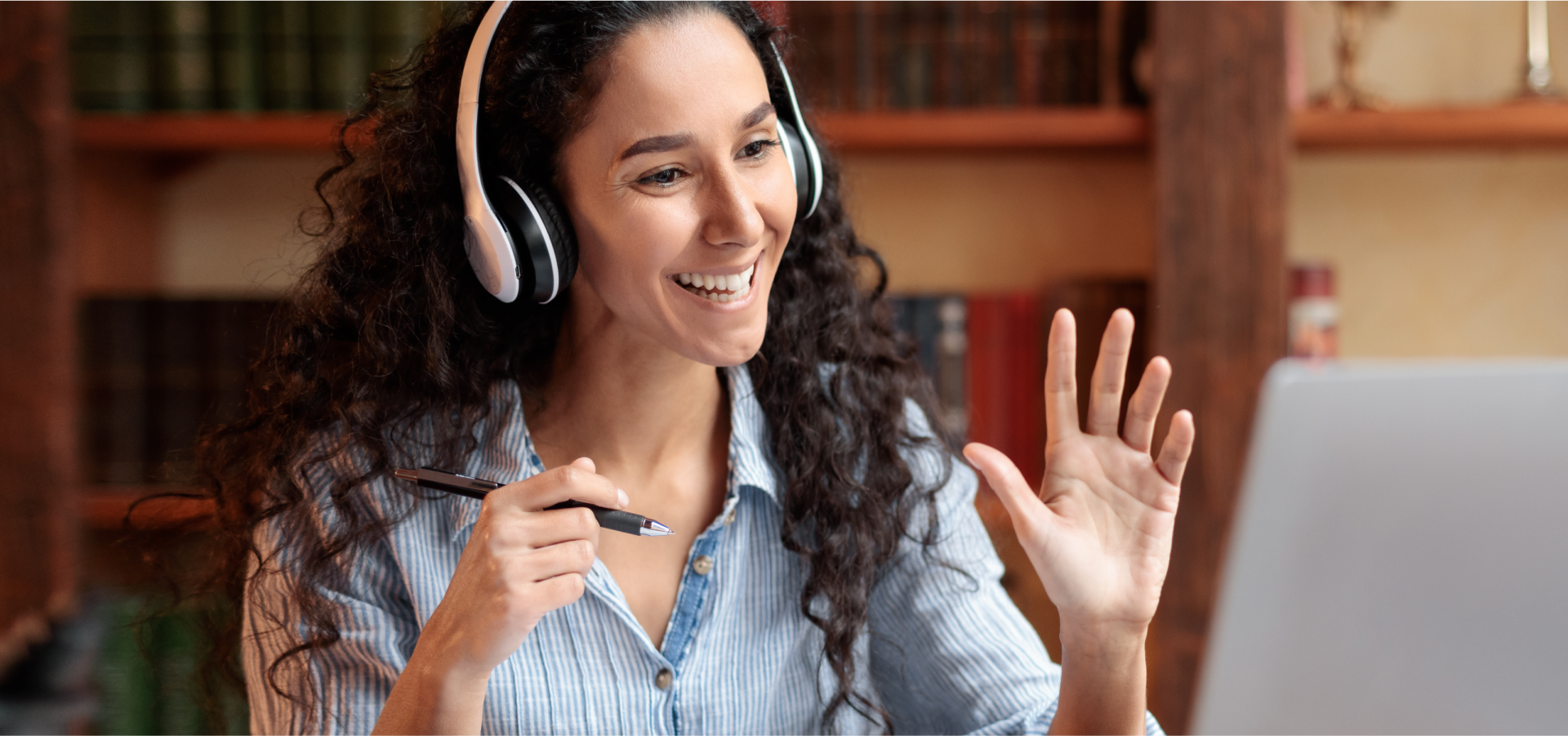 A person sitting at a desk wearing headphones talking animatedly at a person through a computer