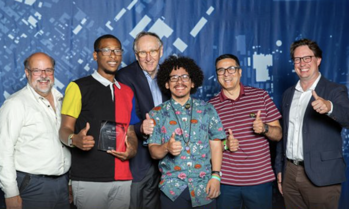 Members of the Hopeworks GIS team smiling and giving a thumbs up while posing with Esri president Jack Dangermond