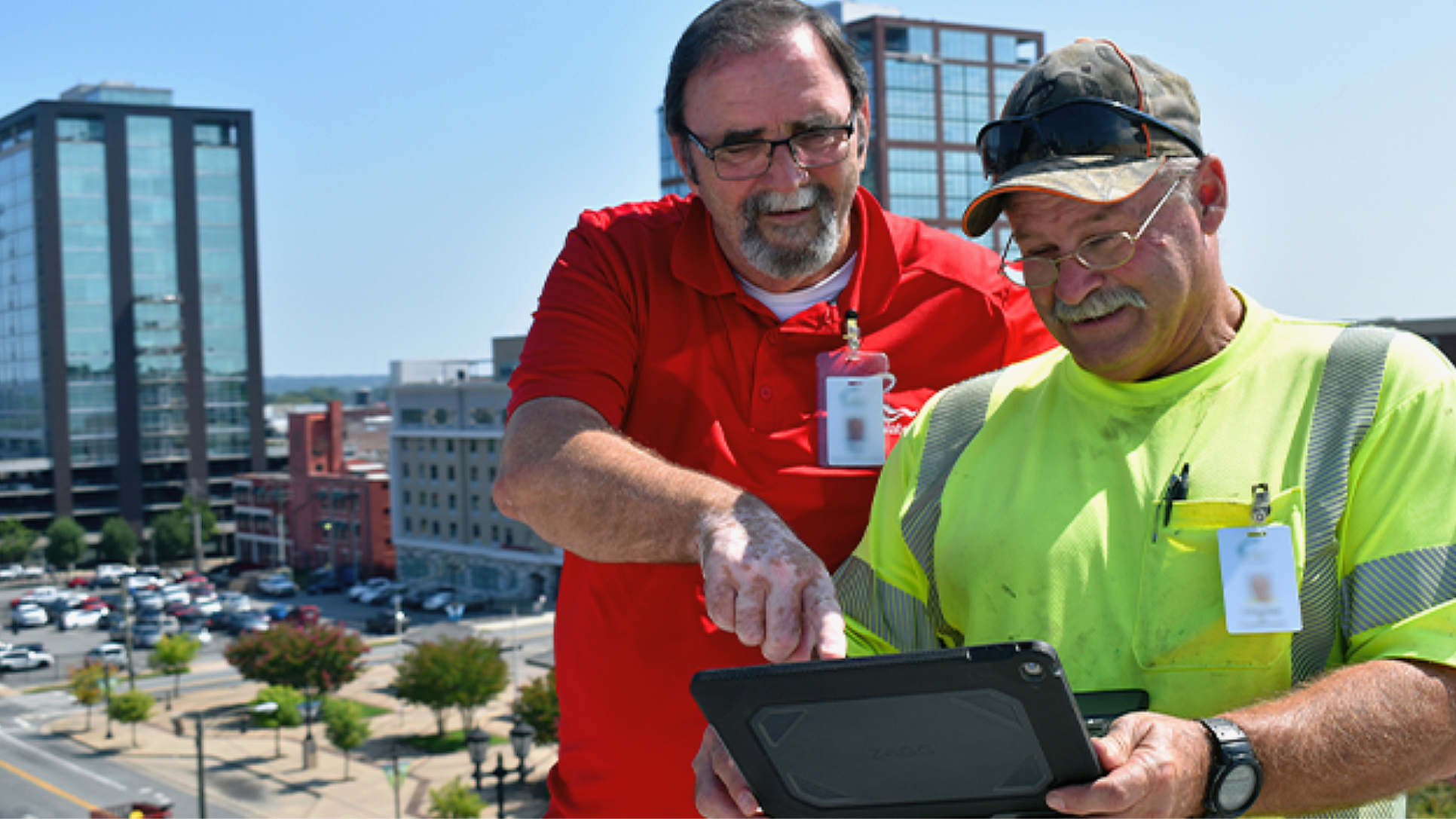 Mitarbeitende eines Versorgungsunternehmens, die im Freien auf einen Tablet-Computer schauen