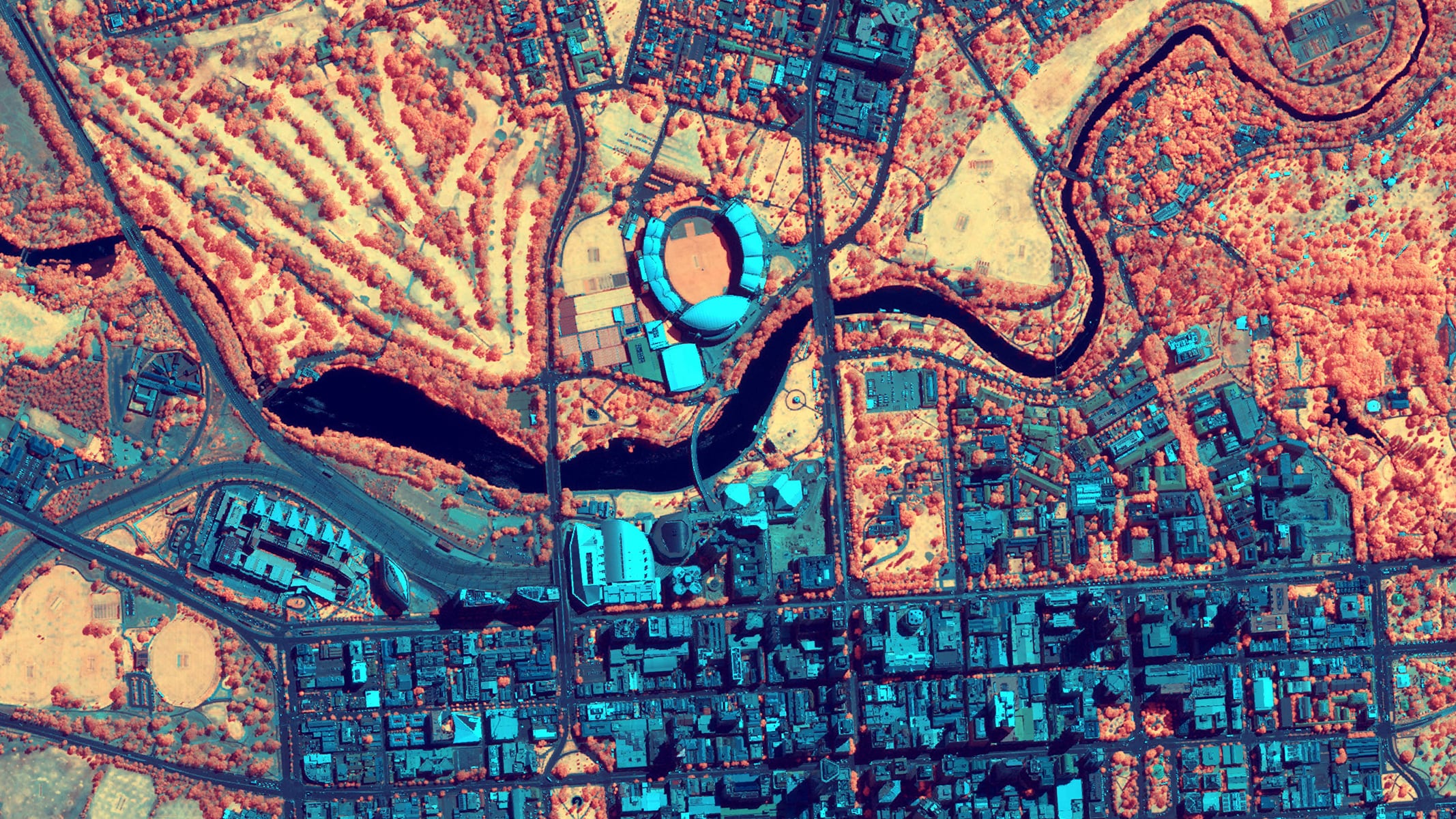 A high-resolution aerial view of a river corridor and surrounding urban landscape displayed in false colors