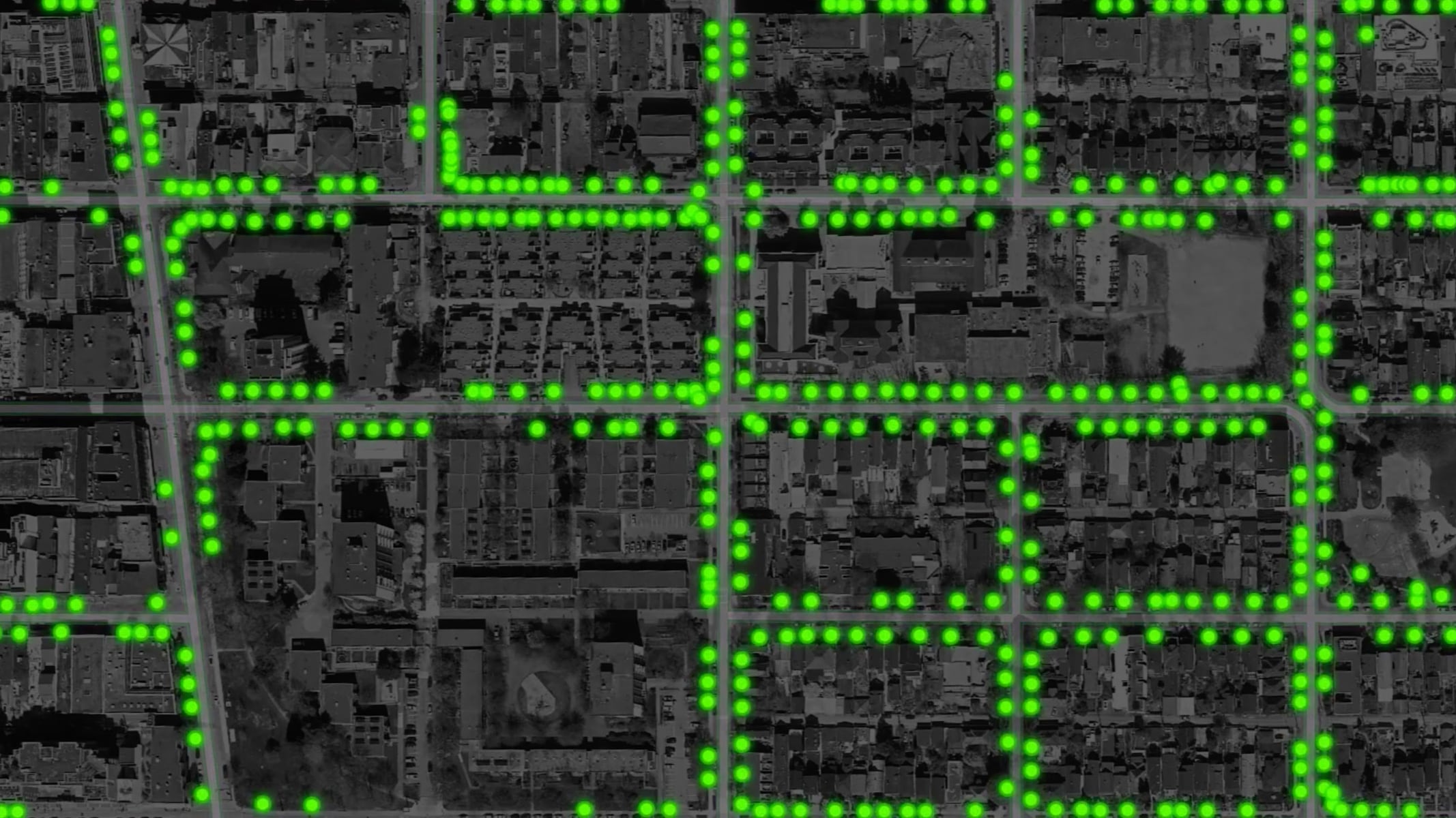 An aerial city view with streets and features highlighted in bright green analysis overlays
