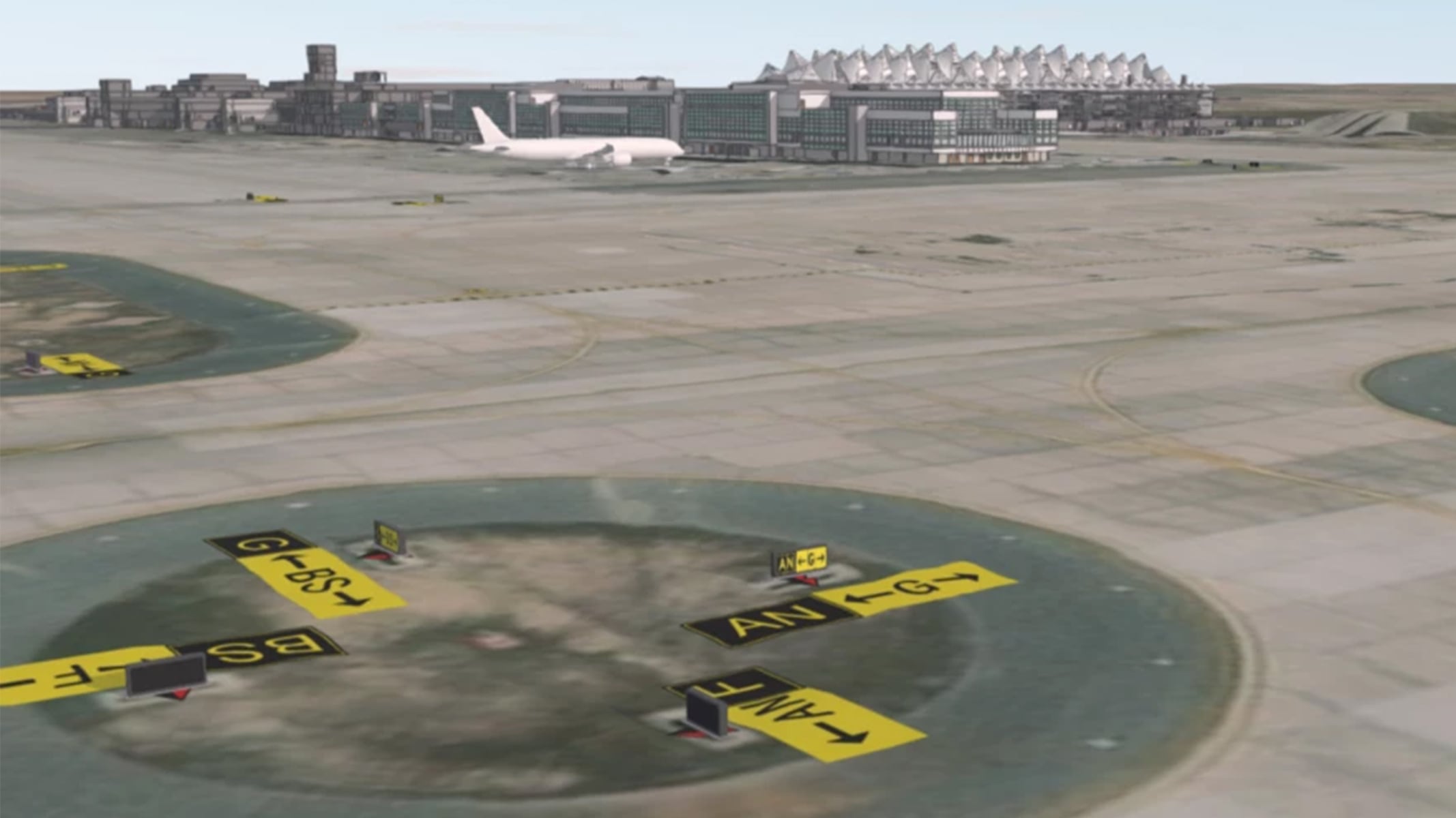 Airside view of Denver Airport with runway directional signs and the terminal in the background