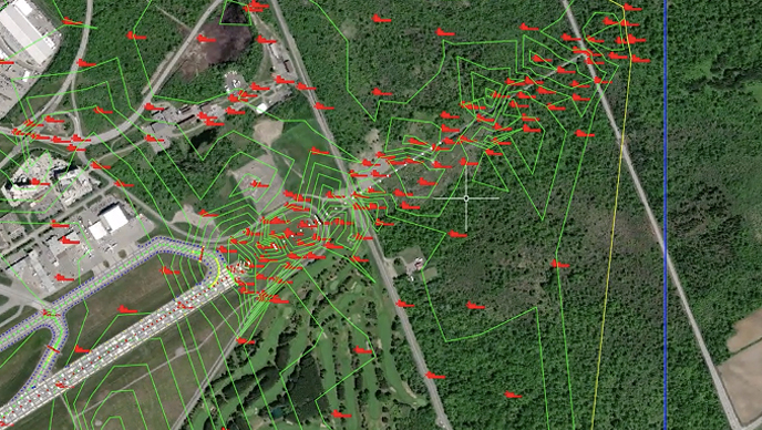 An aerial map of a developed area and forest, marked with green network lines, red flag icons, and a vertical blue and yellow line