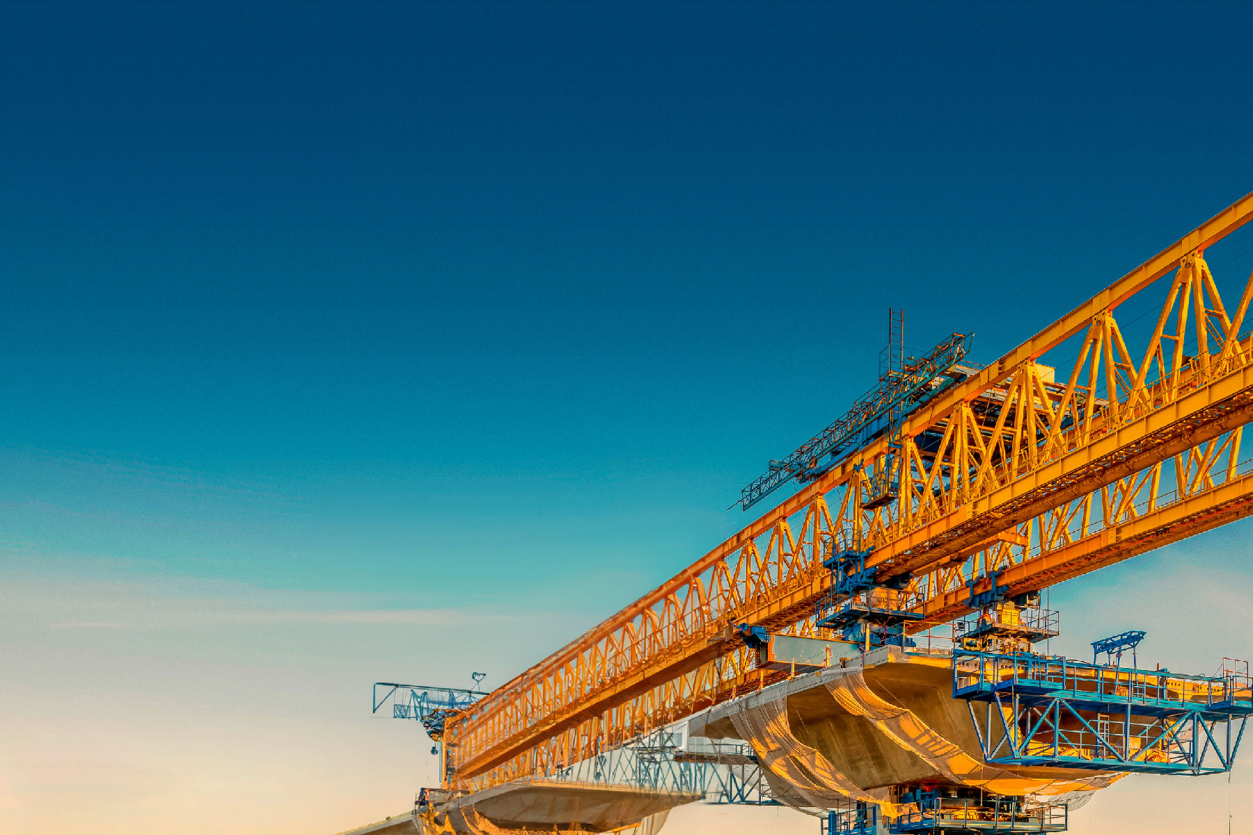 Orange and blue aerial construction equipment including a gantry crane with the sky in the background