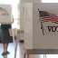 A sunlit room filled with white freestanding voting booths