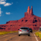 A car driving on a road toward a sandstone mountain