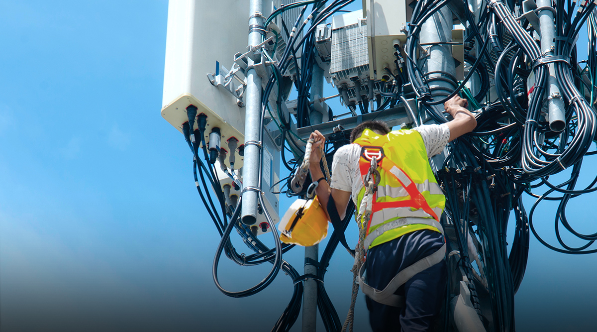 Technician performing maintenance on equipment on a telecommunications tower