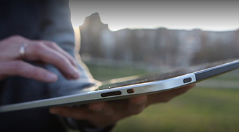 A close-up of a person’s hands using a tablet while outdoors