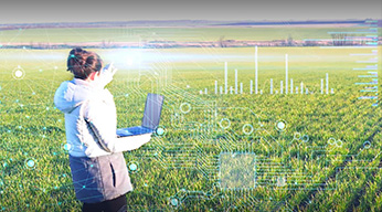 A mobile worker on a laptop while in a field, overlaid by many statistical graphics in white