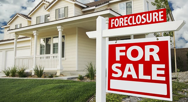 A two-story house with a Foreclosure and For Sale sign in front