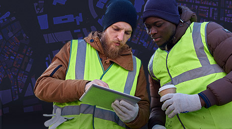 Two men in safety vests looking at a tablet