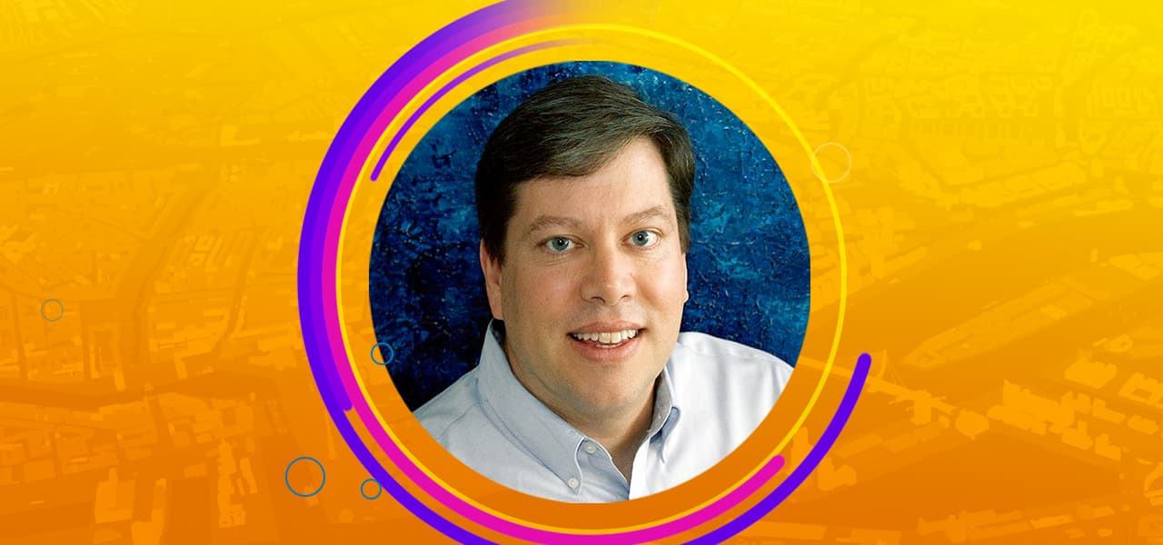 A circular headshot of David Watkins, Esri ArcGIS Pro product manager, enclosed in an orange, purple, and pink design