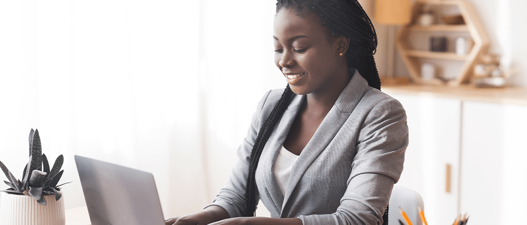 A person in business attire sitting at a table and smiling while working on