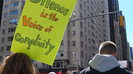 A sign at a protest that reads, “Silence is the voice of complicity”