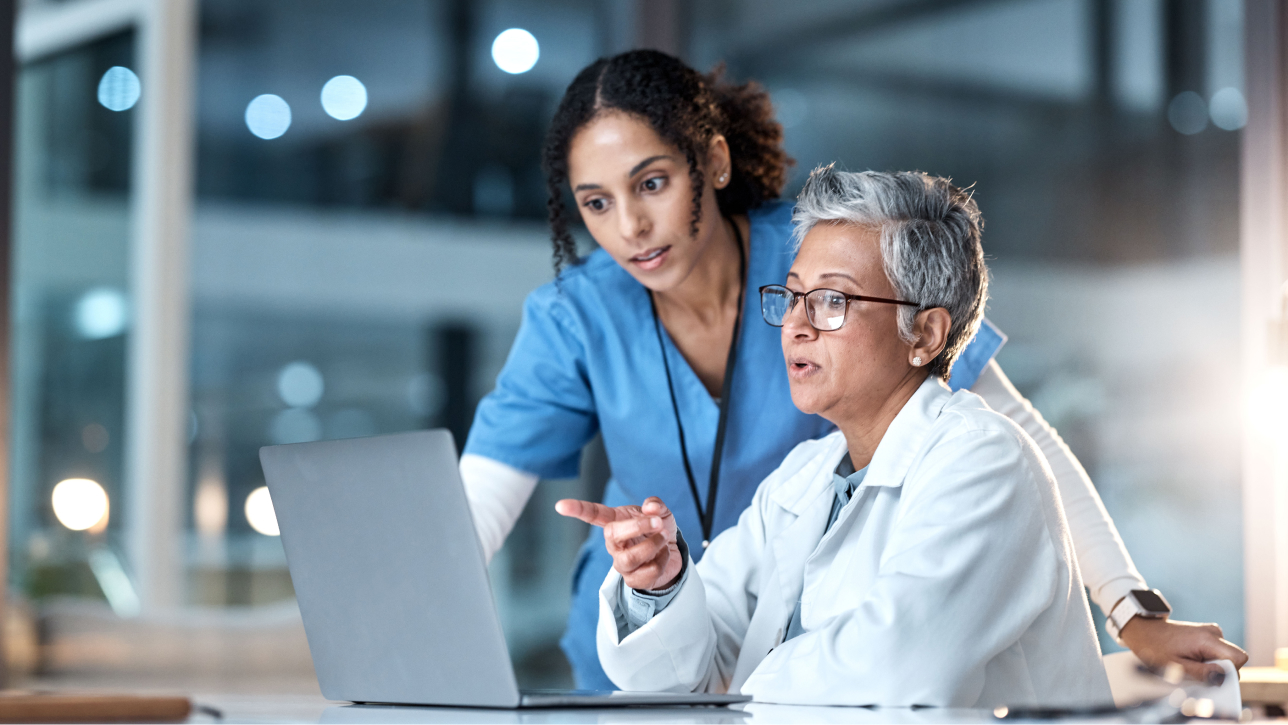 Dois profissionais médicos discutindo a tela de um laptop em uma elegante e moderna sala de conferências de um hospital