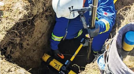 A mobile worker using equipment outside in a ditch