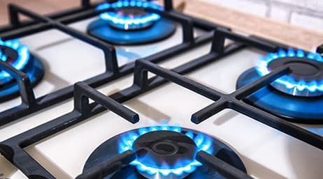 A close-up of a gas stovetop with four burners turned on