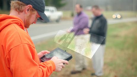 A man using a tablet to analysis data trends on a map.