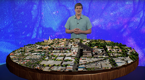 Esri’s Adrien Meriaux standing behind a table that shows a digital 3D model of a city 