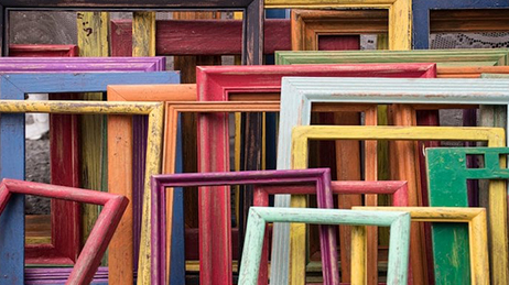 Assorted picture frames in various colors and sizes leaning against a wall