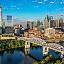 The downtown Nashville skyline near a river and bridge on a sunny day