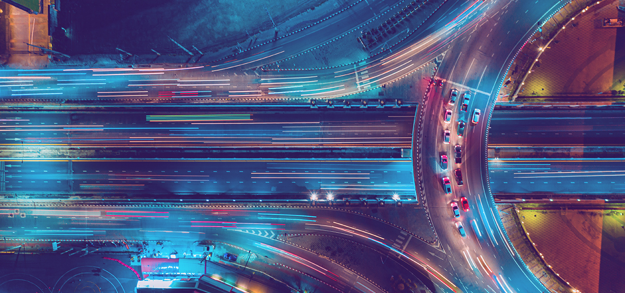 A time lapse photo of cars on a highway, with some cars stopped on a curved overpass