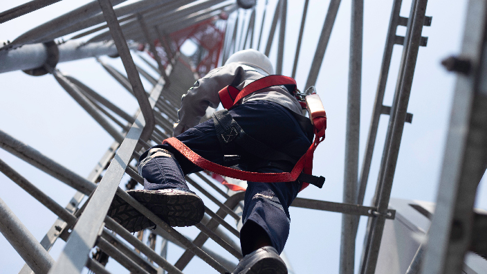Utility worker climbing telecom tower