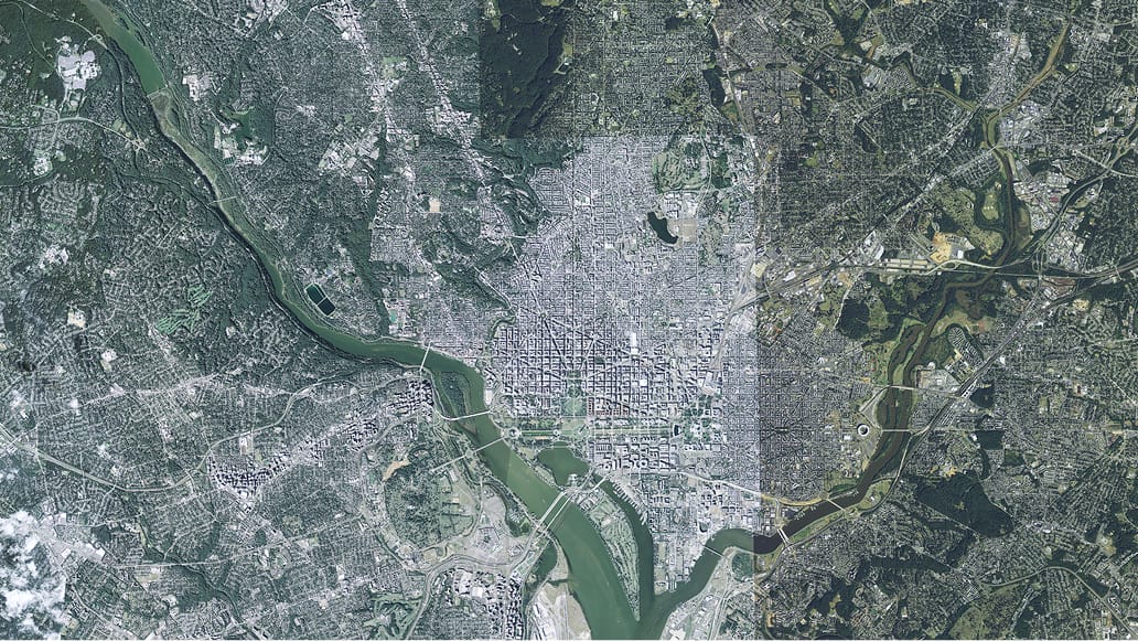 High-resolution satellite image shows a densely populated urban area intersected by a wide river.