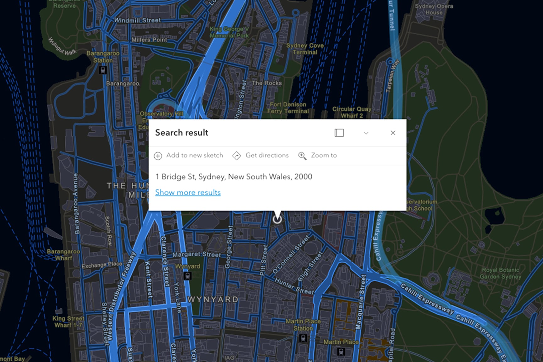 A digital map interface displays a search result centered on an urban area of Sydney, Australia. A white popup box shows the address '1 Bridge St, Sydney, New South Wales, 2000' along with options such as 'Add to new sketch', 'Get directions', and 'Zoom to'. 