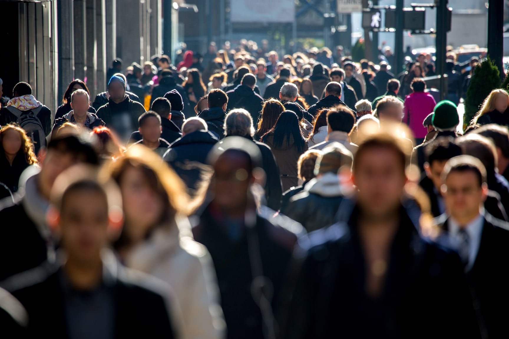 A large crowd of people walking along a city street.