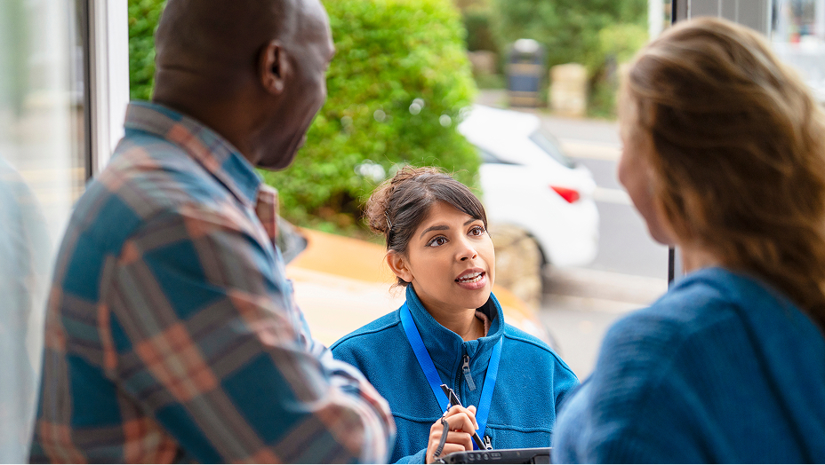 A census worker speaking with residents outside a home.