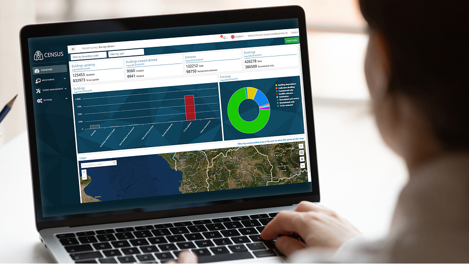 A person using a laptop with maps and analytical dashboards.