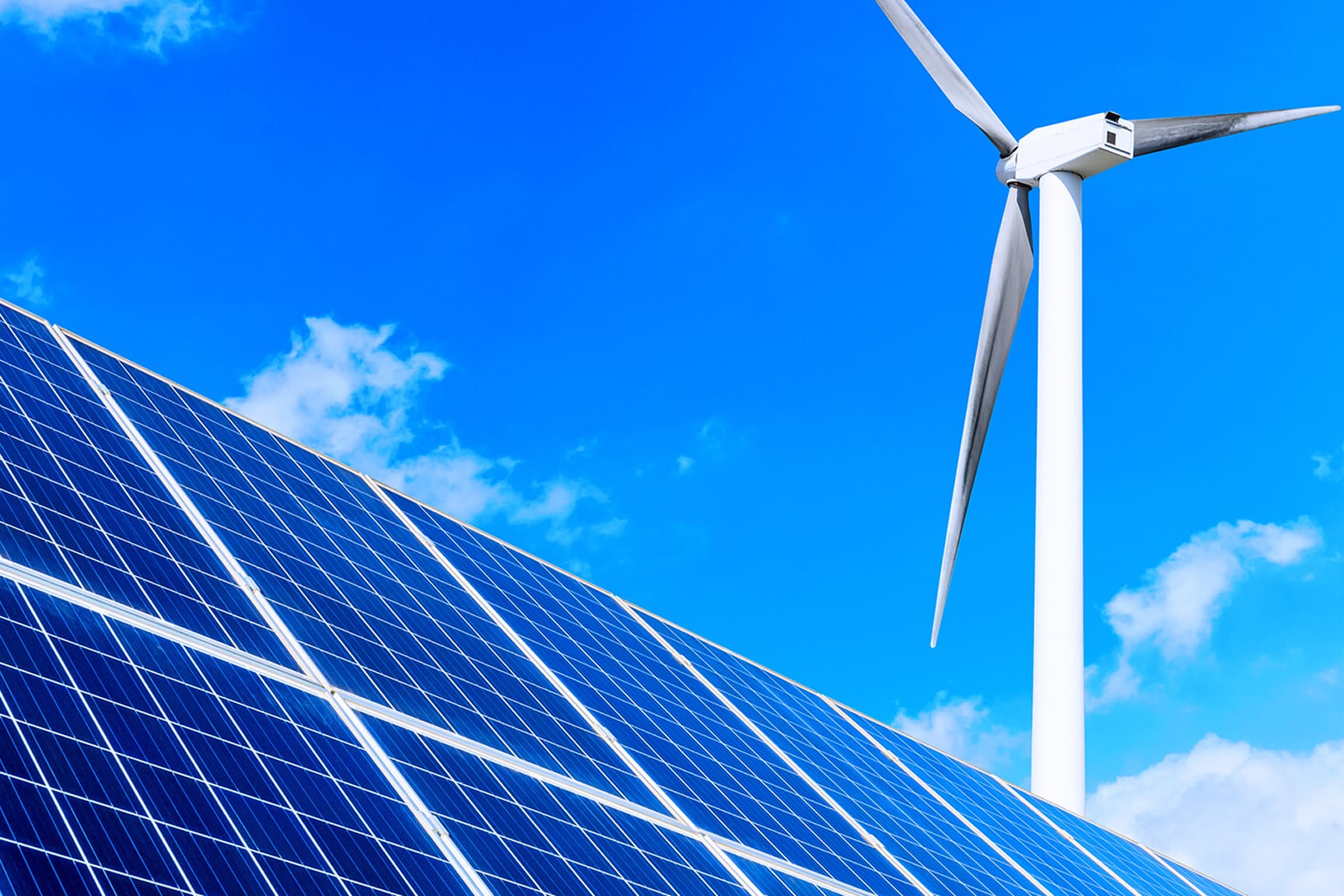The image features a close-up view of solar panels in the foreground with a large wind turbine in the background. 